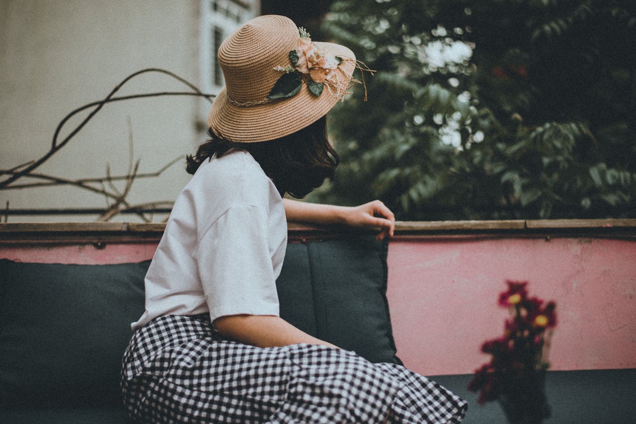 A woman wearing a floral hat enjoys leisure time on a Hanoi balcony, Vietnam.